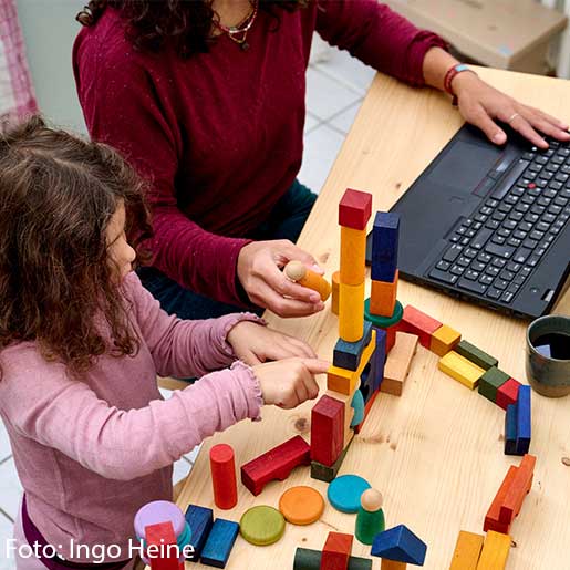 Arbeitende Frau mit spielendem Kind